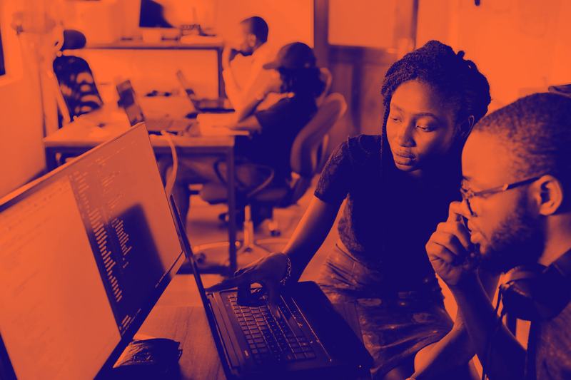Mentor coaching a team member at a laptop